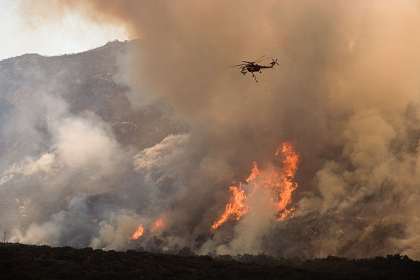 A helicopter drops water on a wildfire in California, Oct 2007 (photo by FEMA via Wikimedia Commons)