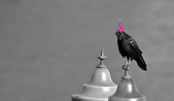 Crow on a spire with an added party hat (photo by Ian Shane via Wikimedia Commons, altered by Kate St.John)